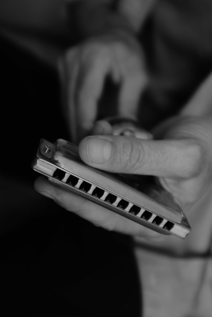 Une photo en noir et blanc d'un harmonica dans les mains de Guillaume Lagger